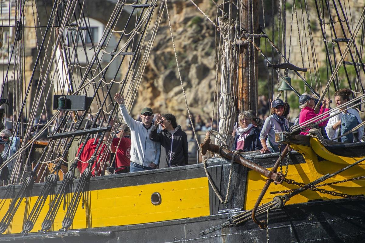 The passengers respond with grand gestures to the applause of the crowd.